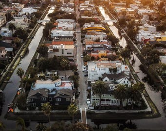 Peut inclure: Vue aérienne d'un quartier avec des canaux qui le traversent. Les maisons sont principalement à un étage et présentent une variété de couleurs. Il y a des palmiers et une végétation luxuriante dans tout le quartier.