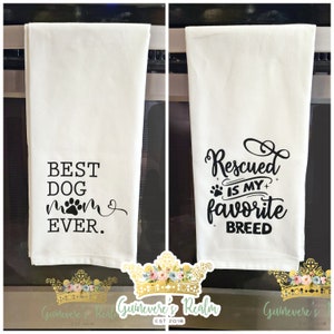 May include: Two white kitchen towels with black text. One reads "BEST DOG MOM EVER" with a paw print. The other says "Rescued IS MY favorite BREED" with a paw print. Both towels are hanging.