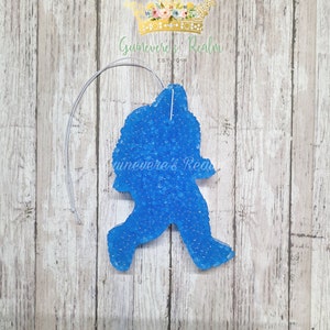 May include: A blue car air freshener shaped like a person walking. The air freshener is made of a gel-like material with a string for hanging.