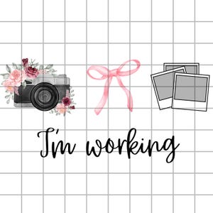 May include: A digital camera with floral accents, a pink bow, and two blank polaroid-style photos are arranged on a grid background. The phrase "I'm working" is written in cursive below the objects.