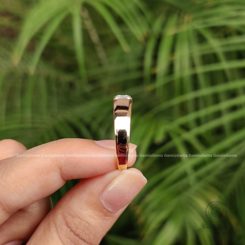 May include: A rose gold ring with a smooth, polished band and a rectangular setting at the top. The metal has a warm, metallic sheen, and the design features a clean, minimalist profile with a flat top surface visible from the side view.