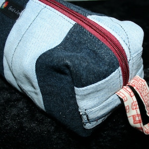 May include: A striped denim pencil case with a red zipper and a white tag that says "Made in Love".