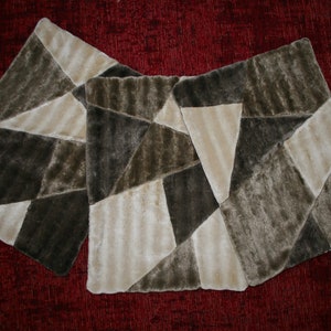 Könnte beinhalten: Drei beige und braune Kunstfell-Wurfkissen mit geometrischem Muster. Die Kissen sind in Dreiecksform angeordnet.