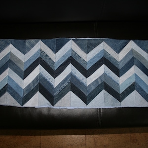 Könnte beinhalten: Ein langer, rechteckiger Denim-Teppich mit Chevron-Muster. Der Teppich besteht aus verschiedenen Blautönen von Denim und weißem Stoff.