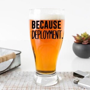 May include: A clear glass beer mug with a black inscription that reads "Because Deployment."