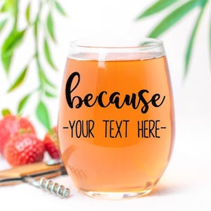 May include: A clear glass wine glass with a light orange liquid inside. The glass has a black vinyl decal that says "because -YOUR TEXT HERE-"