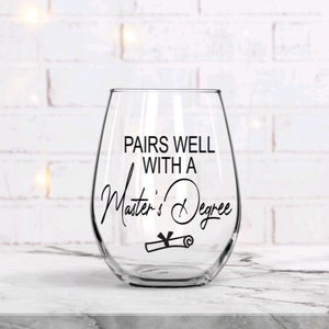 May include: A clear glass wine glass with the text "Pairs well with a Master's Degree" and a graduation cap and diploma graphic.