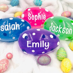 May include: Four plastic Easter eggs with white polka dots and personalized names: Isaiah, Sophie, Jackson, and Emily. The eggs are on a white fluffy surface with other decorative Easter eggs.