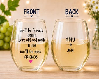 May include: Two clear stemless wine glasses filled with white wine. The left glass features black text reading we'll be friends UNTIL we're old and senile THEN we'll be new FRIENDS with a pink heart. The right glass features the black text AMY & JEN.