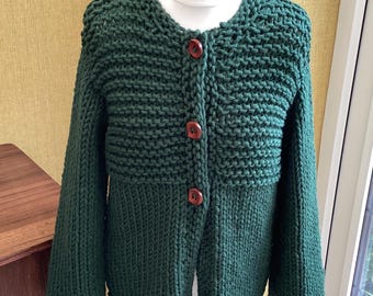 May include: A dark green knitted cardigan with a button-up front and long sleeves. The cardigan has a slightly puffed sleeve and a ribbed texture.