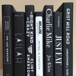 May include: A collection of hardcover books with black covers and white lettering. Titles include "The Last Magazine," "Lailah," "The Right Kind of Crazy," "Selling Nostalgia," "Charlie Mike," "Just Eat," and "Grist Mill Road."