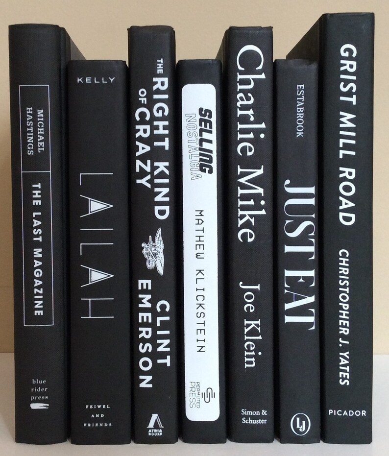 May include: A collection of hardcover books with black covers and white lettering. Titles include "The Last Magazine," "Lailah," "The Right Kind of Crazy," "Selling Nostalgia," "Charlie Mike," "Just Eat," and "Grist Mill Road."