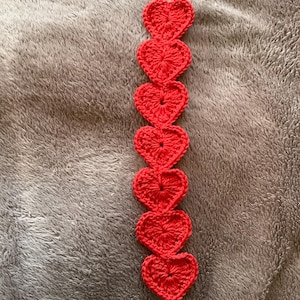 May include: A red crocheted bookmark with a series of connected hearts.