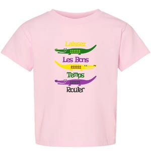 Puede incluir: Camiseta rosa con un gr&aacute;fico de cuatro caimanes con el texto "Laissez Les Bons Temps Rouler" impreso en ella.