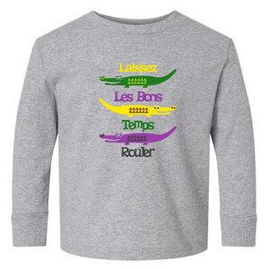 Puede incluir: Una camiseta gris de manga larga con un gr&aacute;fico de cuatro caimanes y el texto "Laissez Les Bons Temps Rouler" en amarillo, verde y morado.