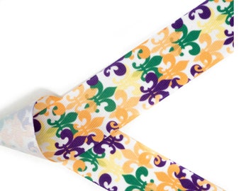 May include: White ribbon with a repeating pattern of fleur-de-lis in purple, green, and yellow.