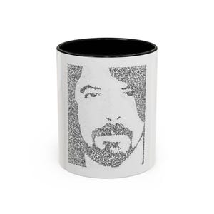Puede incluir: Taza de cerámica blanca con interior negro. La taza presenta un retrato en escala de grises de un hombre con barba, creado a partir de un patrón de texto pequeño. La taza es de tamaño estándar para bebidas calientes.