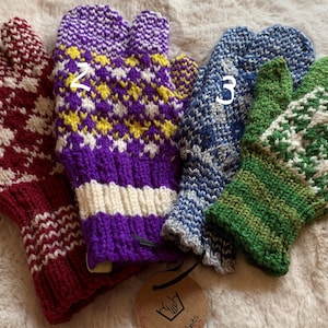 Può includere: Quattro paia di guanti senza dita a maglia in diversi colori e motivi. I guanti sono rosso e bianco, viola e giallo, blu e bianco e verde e bianco.
