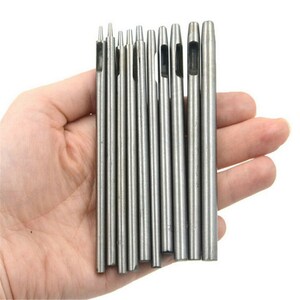 May include: A set of 10 silver metal hole punch tools with different sized holes. The tools are held in a hand.