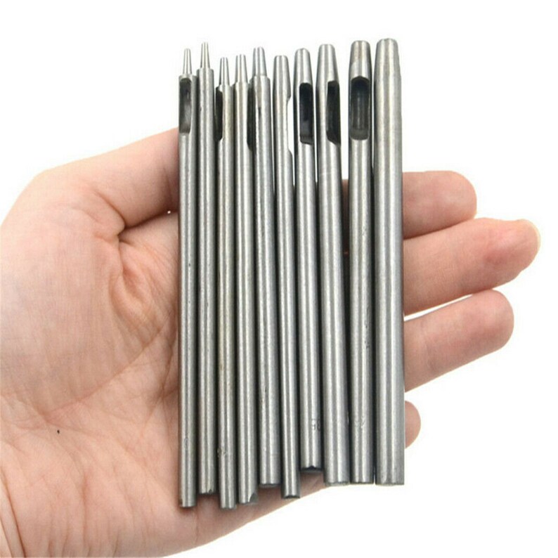 May include: A set of 10 silver metal hole punch tools with different sized holes. The tools are held in a hand.