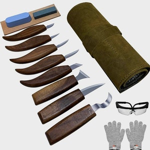 May include: A set of 8 wood carving tools with brown wooden handles and a variety of blade shapes. The tools are rolled up in a brown leather case. The set also includes a pair of safety glasses and a pair of gray work gloves.