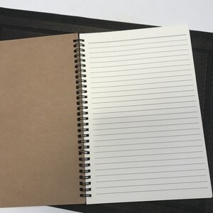May include: A brown and white spiral bound notebook with lined pages. The notebook is open to a blank page.