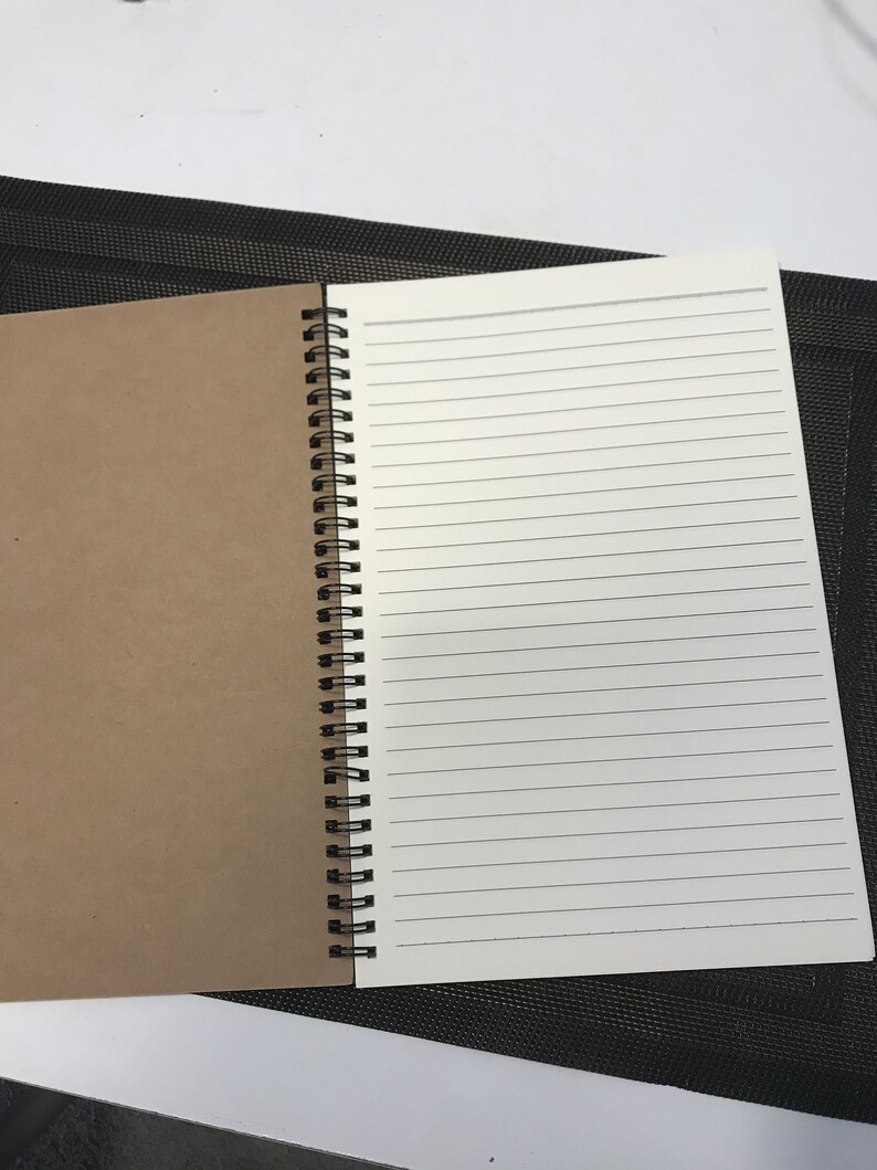 May include: A brown and white spiral bound notebook with lined pages. The notebook is open to a blank page.