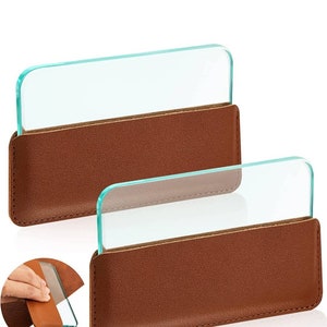 May include: Two clear glass magnifying sheets with brown leather cases. The cases have a stitched edge and are closed with a flap.