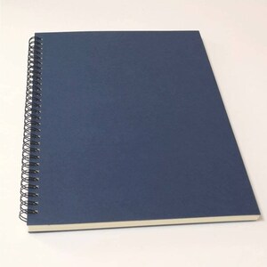 May include: A dark blue spiral bound notebook with a white edge.