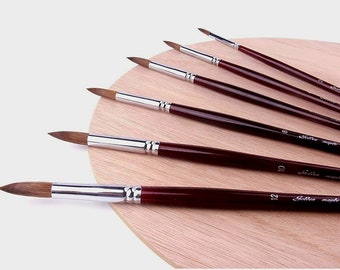 May include: Set of six round-tipped paint brushes with brown wooden handles and silver metal ferrules. The brushes are arranged on a wooden palette. The handles are labeled with the numbers 6, 8, 10, and 12. The text "Golden Maple" is printed on the handles.