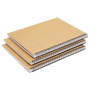May include: Three brown spiral bound notebooks stacked on top of each other.