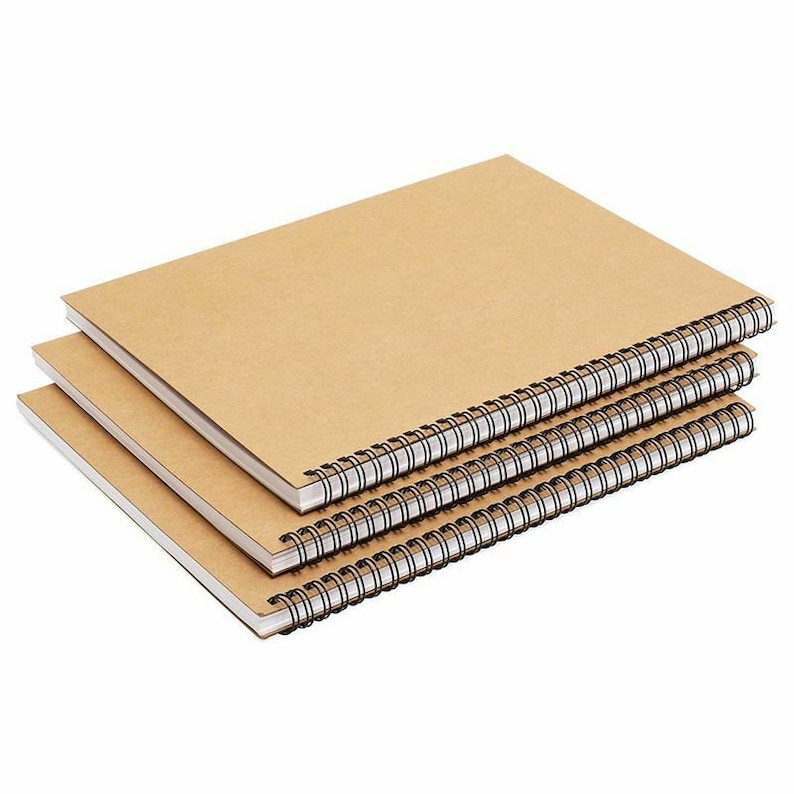 May include: Three brown spiral bound notebooks stacked on top of each other.