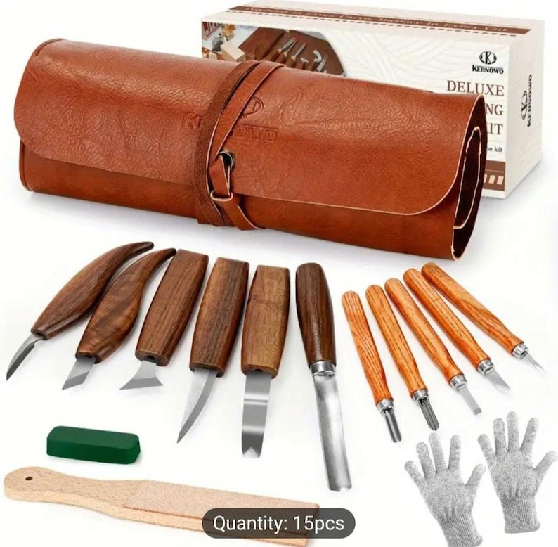 Pu&ograve; includere: Un set di 15 strumenti per intagliare il legno con un astuccio arrotolabile in pelle marrone. Gli strumenti hanno manici in legno e lame in metallo. Il set include anche una pietra per affilare verde, un blocco di levigatura in legno e un paio di guanti da lavoro grigi. L'astuccio ha una cinghia in pelle marrone con una fibbia in metallo. Il testo "Quantity: 15pcs" &egrave; stampato nella parte inferiore dell'immagine.