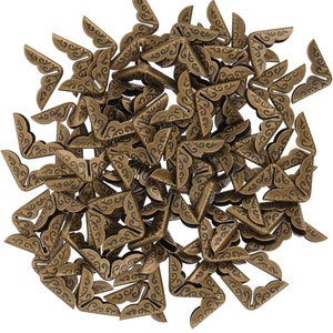 May include: A pile of antique gold-toned metal corner protectors with a decorative floral design.