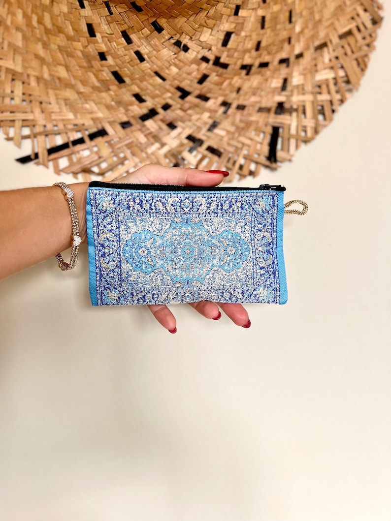 May include: A small blue and white patterned zippered pouch with a gold zipper pull.