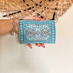 May include: A small blue and white patterned zippered pouch with a gold zipper pull.