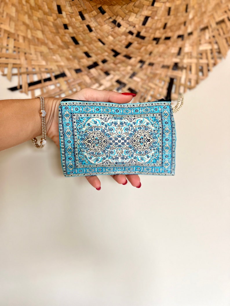 May include: A small blue and white patterned zippered pouch with a gold zipper pull.