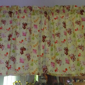 May include: A yellow valance curtain with a repeating pattern of cartoon animals, including giraffes and pigs. The curtain is mounted on a white rod and has a gathered top. The animal print includes red, pink, and green accents.