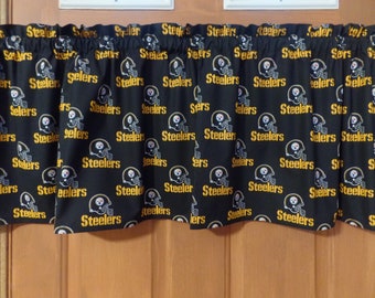 May include: Black valance featuring a repeating pattern of the Pittsburgh Steelers logo and the team name in gold. The valance is designed to fit over a window or door, adding a touch of team spirit to any room.