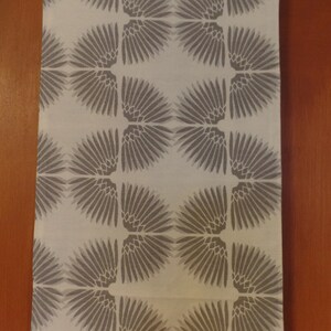 May include: White fabric kitchen towel with a repeating pattern of gray stylized feathers.