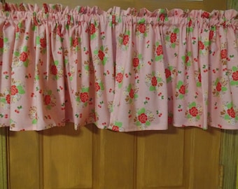 May include: Pink valance with a floral pattern featuring red roses, green leaves, and white dots. The valance has a ruffled edge.