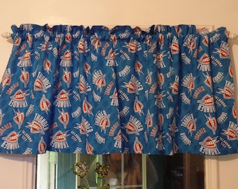 May include: Blue valance curtain with a repeating pattern of the Oklahoma City Thunder logo in red, white, and orange. The valance is mounted on a white rod above a window.