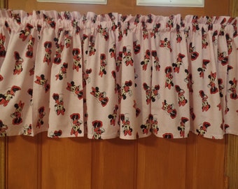 May include: Pink valance with a Minnie Mouse print. The valance features a repeating pattern of Minnie Mouse in various poses with red polka dots on a pink background.
