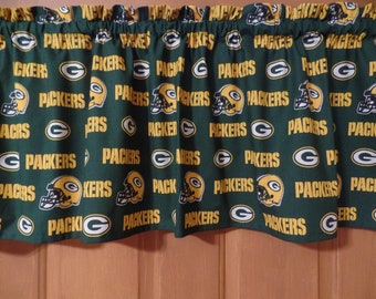 May include: Green and gold fabric valance with a repeating pattern of the Green Bay Packers logo. The logo features a football helmet with a 'G' on the side and the words 'Packers' underneath.