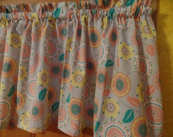 May include: A gray valance with a floral pattern featuring peach, yellow, and teal colors. The valance has a gathered ruffle at the top.