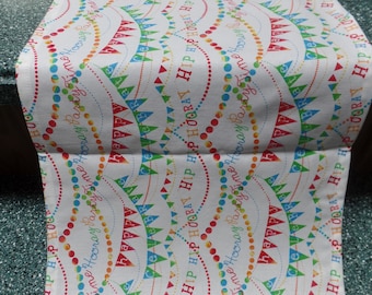 May include: White table runner with a repeating pattern of colorful flags and the words "Hip Hooray Party Time" in a red, blue, green, and yellow font.