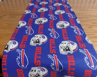 May include: Blue table runner with a repeating pattern of white football helmets and the words "Bills" in red.