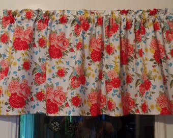 May include: A white valance with a floral pattern featuring red, pink, and yellow flowers on a white background. The valance has a ruffled edge and is made of a lightweight fabric.