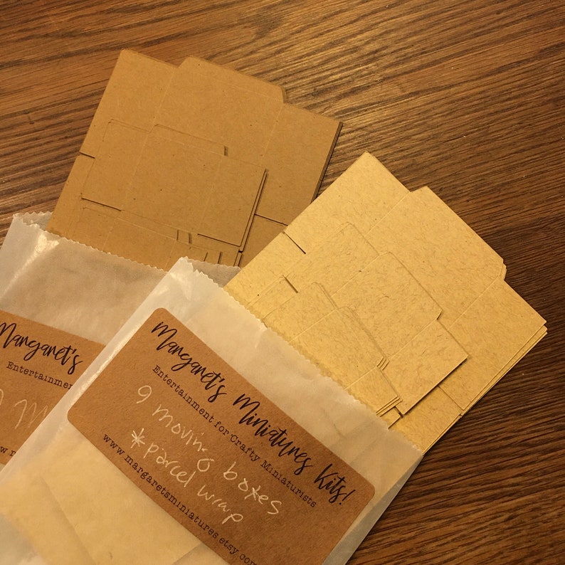 May include: Miniature moving box kits, including 9 boxes and parcel wrap, are displayed in the image. The kits are packaged in white paper bags with a brown label that reads "Margaret's Miniatures Kits!" and the Etsy website address.