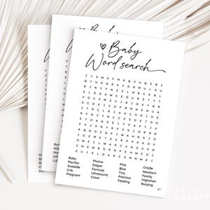 May include: Three white paper sheets with a baby-themed word search game. The top sheet has the words "Baby Word Search" in cursive. The word search includes words like "diaper," "crib," and "formula." A decorative palm leaf is in the background.